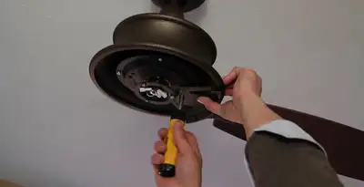 Electrician installing ceiling fan mounting bracket and fixture in Raleigh, NC