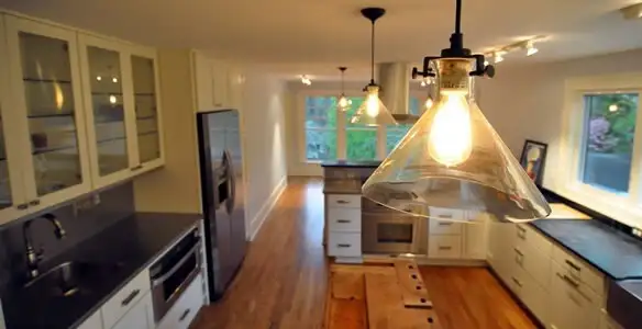 Residential electrician installing modern indoor light fixture in a home in Raleigh, NC